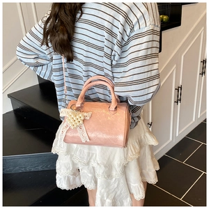 Detailed view of pink Boston bag with lace bow and pearl heart charm on a model