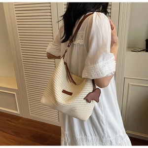 Detail of white crochet knit tote bag with brown leather straps and cute sheep pendant