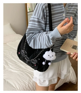 Detail of black velvet shoulder bag with cute cartoon patches and silver chain strap