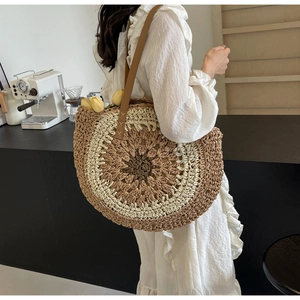 Detail van de bohemian ronde strooien tas met contrasterend vlechtwerk en lederen schouderriem