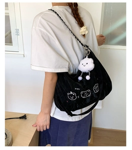 Detail view of black canvas shoulder bag with cartoon bear print and fluffy cloud charm