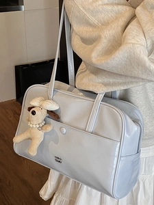 Light blue patent leather shoulder bag with logo and cute plush puppy charm worn by model
