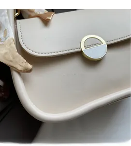Vue détaillée du sac en cuir crème avec boucle en émail doré et foulard en soie décoratif