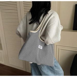 Close-up of black and white striped canvas tote bag with woven logo label and beige trim