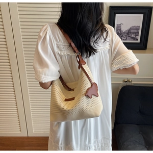 Detail of hand-woven beige tote with brown leather strap and stylish charms on a model