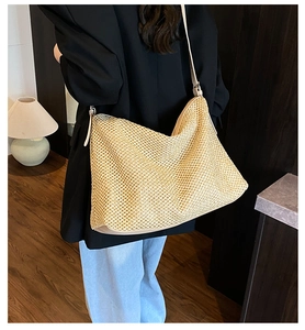 Detailed view of the large woven straw tote bag texture and long shoulder straps