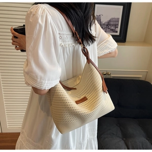 Detail of straw woven tote with brown leather strap and knotted shoulder design