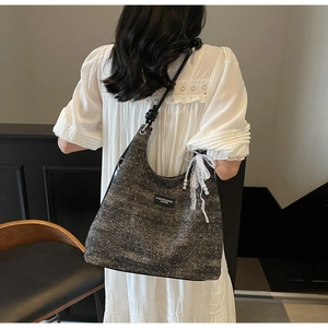 Detail view of tweed shoulder bag with pearl accents and lace bow on female model