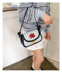 Detail of blue plaid saddle bag with red apple pattern and Not anxious text design