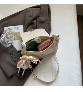 Détail de l'intérieur d'un sac bandoulière crème en PU montrant la capacité et le foulard de soie