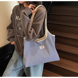 Detail of blue and white striped tote bag with wide strap on a wooden staircase
