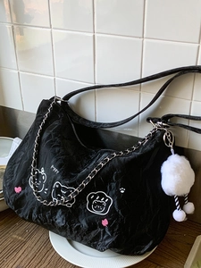 Chic black pleated underarm bag with puppy graphics and plush pompom charm