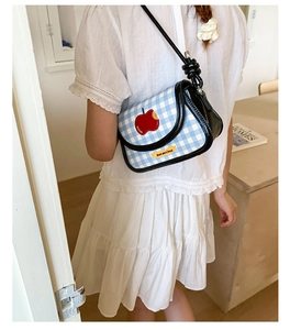 Close-up of blue plaid saddle bag with red apple patch and decorative shoulder strap knot