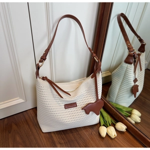 Detail of woven straw hobo bag featuring leather shoulder strap and brown bear charm