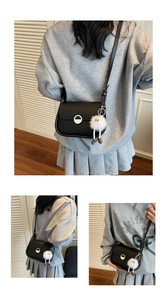 Détail du petit sac carré en cuir noir avec boucle argentée et charm monstre en peluche