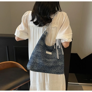 Close-up of blue denim tote bag with white studs and silver twisted handle details