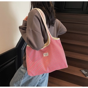 Red and white vertical striped canvas tote bag with wide strap on a female model