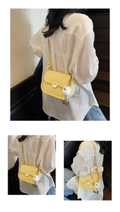 Détail du sac besace en cuir jaune avec boucle métallique et pendentif en peluche