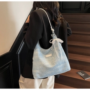 Blue sequin shoulder bag with white lace bow and pearl detail shown on a model