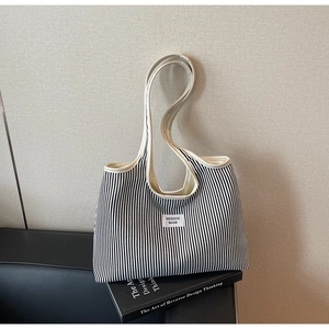 Detailed close-up of a striped canvas tote bag on a book with the Wegoco brand label