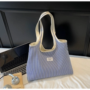 Detailed close-up of blue and white striped canvas tote bag with woven logo label