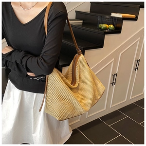 Detail of large straw tote bag featuring geometric folding and brown leather straps