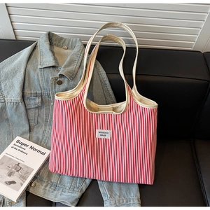Detailed macro view of large red and white striped canvas tote bag with woven logo on leather