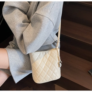Détail du sac seau matelassé crème avec cordon de serrage et breloque cœur en argent