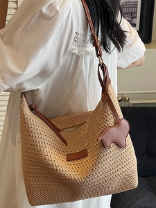 Fashionable woven straw tote bag with brown leather straps and elephant charm