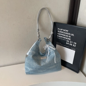 Detail of light blue denim tote with silver handles and white lace bow decoration