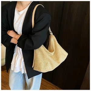 Close-up of woven straw tote bag featuring natural texture and white leather shoulder strap