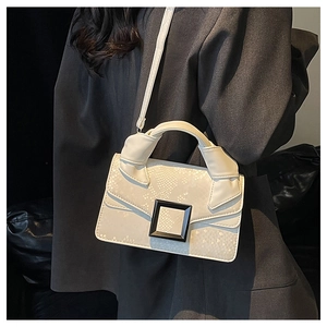Détail du sac à main beige texture serpent avec boucle noire sur une veste oversize
