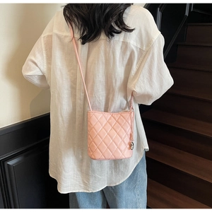 Sac seau rose matelassé avec coutures en losange et pendentif porté par modèle