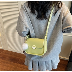 Vue portée du sac bandoulière vert en cuir avec pompon blanc et bandoulière ajustable