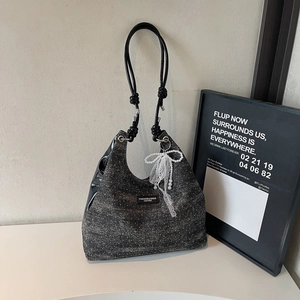 Detail of black shimmer fabric hobo bag with white lace bow and pearl pendant charm