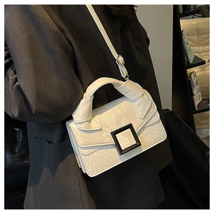 Détail d'un sac bandoulière blanc à texture serpent avec une boucle carrée noire mate