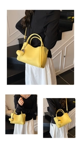 Détail du sac seau jaune à motif litchi avec breloque coeur et bandoulière amovible