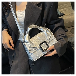 Détail du sac à main argenté à motif serpent avec une grande boucle carrée noire chic