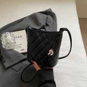 Détail rapproché du sac seau noir matelassé avec pendentif en métal liquide