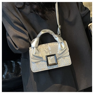 Mini sac à main argenté à motif serpent avec bandoulière porté sur un blazer sombre