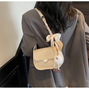 Détail du sac crème avec bandoulière chaîne foulard en soie et pendentif peluche monstre