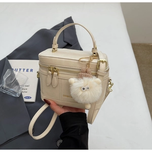 Dettaglio borsa vanity beige con ciondolo di peluche e tracolla rimovibile