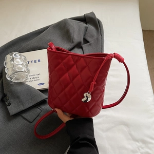 Vue détaillée d'un sac seau rouge matelassé avec surpiqûres diamant et breloque en S
