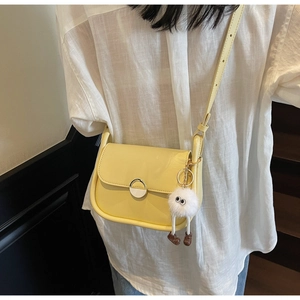 Détail du sac besace jaune clair avec un charmant porte-clés monstre en peluche