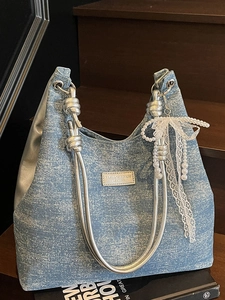 Blue denim tote bag with silver knotted handles and lace pearl bow on wooden stairs