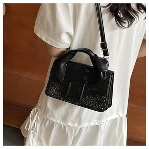 Détail du sac à main noir en cuir serpent avec boucle carrée et poignée nouée design