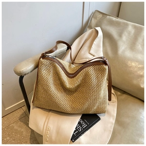 Detail of woven straw shoulder bag with brown leather trim and adjustable strap design