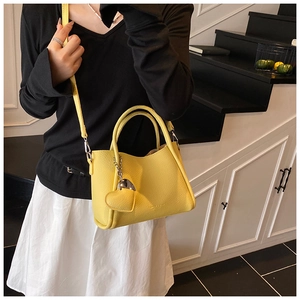 Détail du sac seau en cuir jaune grainé avec pendentif cœur et finitions argentées