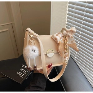 Détail du petit sac crème avec fermoir doré, foulard à pois et pendentif en peluche doux