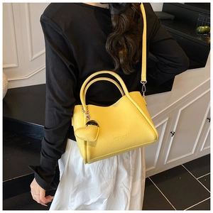 Détail du sac seau jaune vif en cuir litchi orné d'un pendentif en forme de cœur